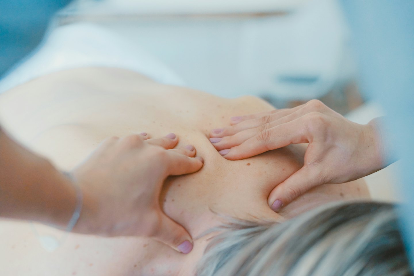 Hands giving a back and shoulder massage.